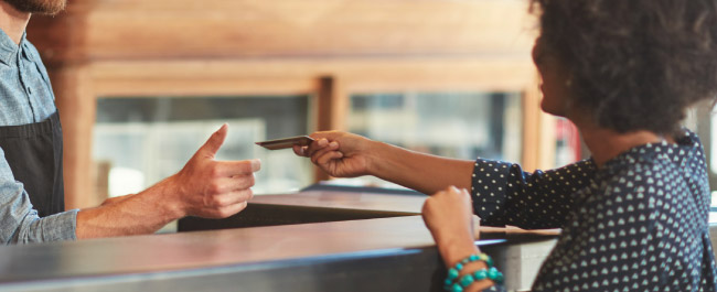 A lady paying a gentleman with a debit/credit card.