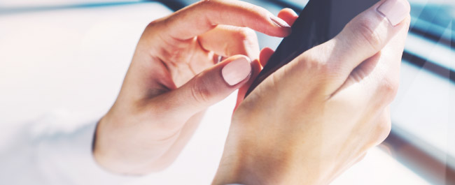 A women's hands holding her mobile phone.