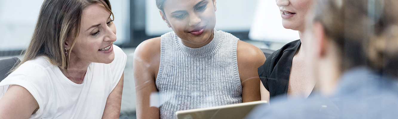 women in meeting looking at tablet