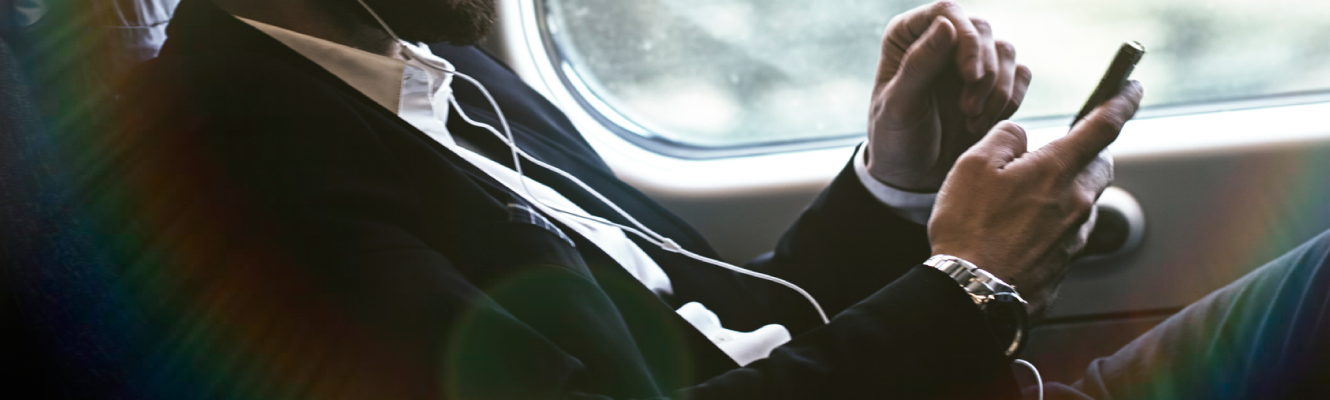 A business man on his smart phone on a train.