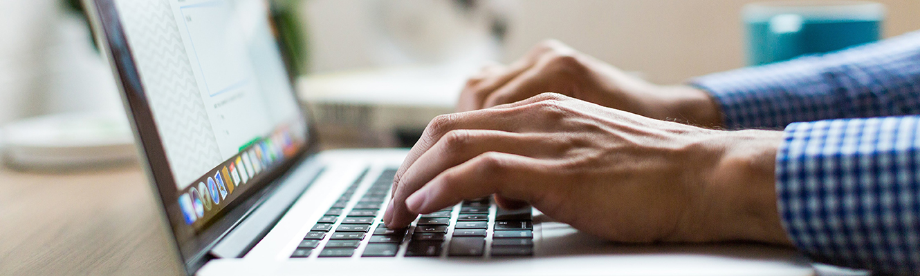 Mans hands typing on laptop