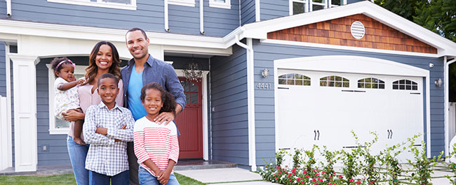 Family standing in front of house smiling